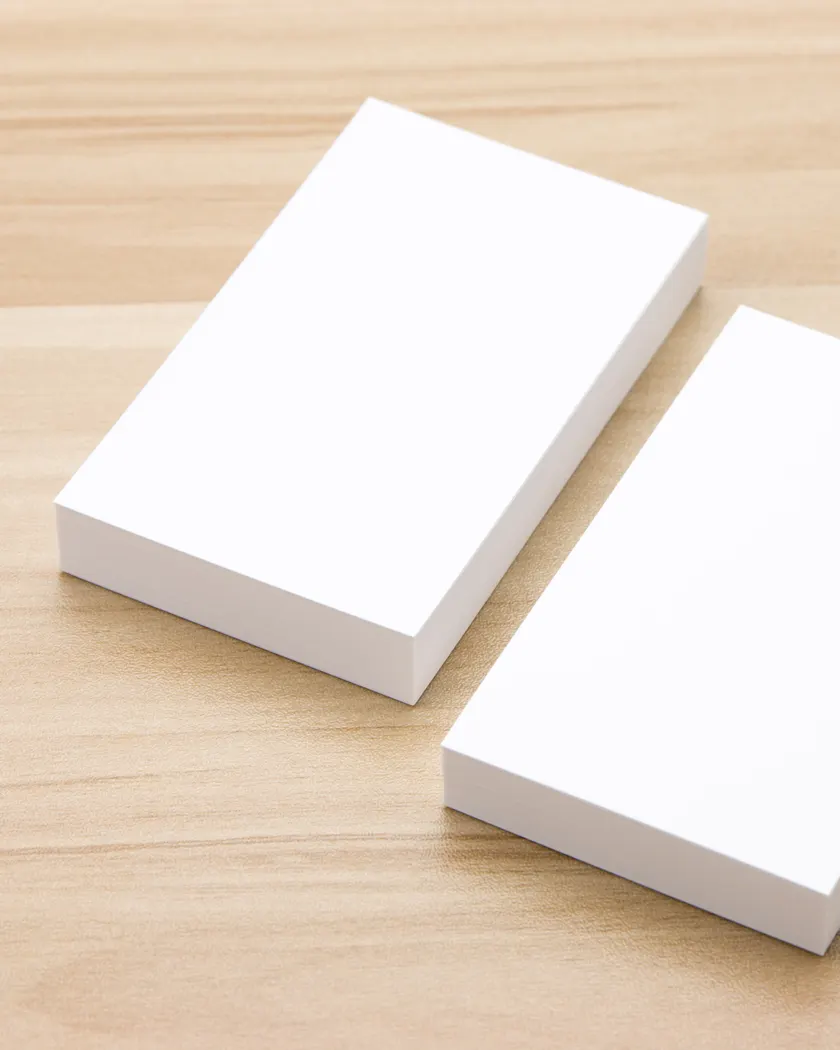 Two stacks of blank business cards on a timber desk