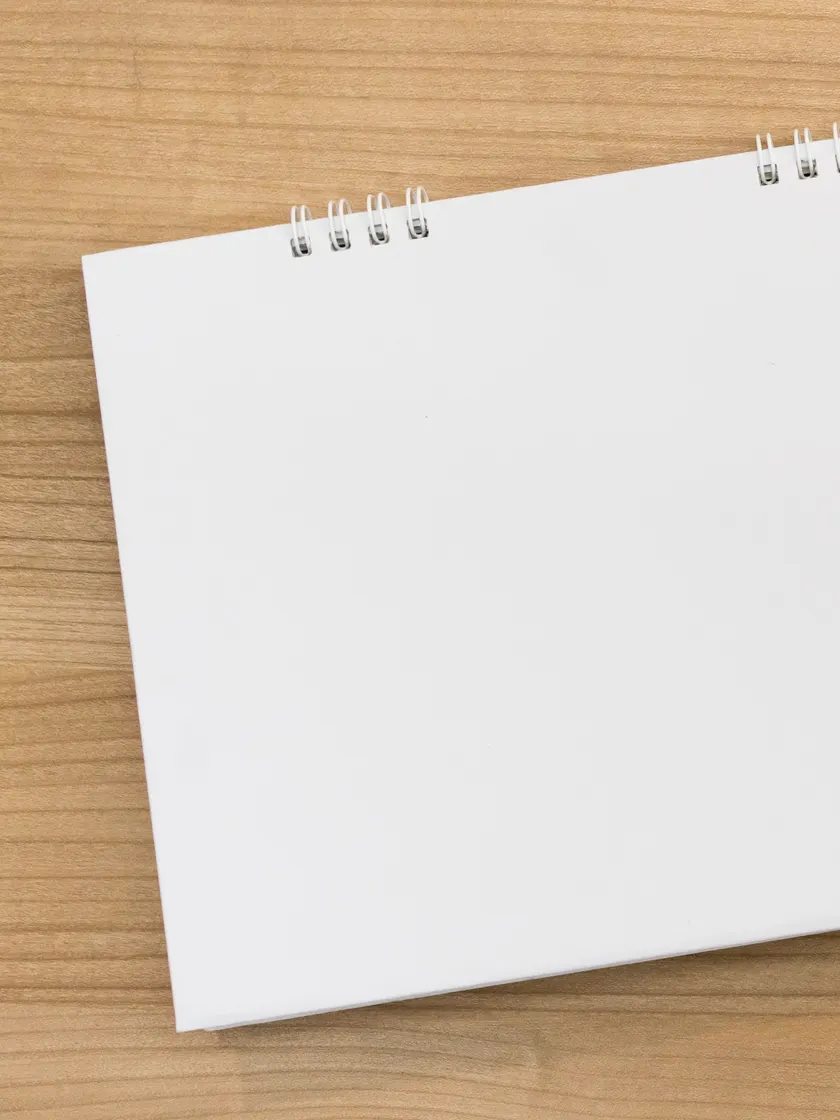 A blank notepad and a pencil on a timber desk